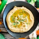 Vibrant vegetable platter with carrots, cucumbers, and celery sticks served alongside a bowl of tahini-free hummus.