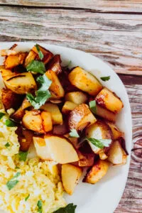 Golden fried leftover potatoes in a cast iron skillet with sautéed onions.