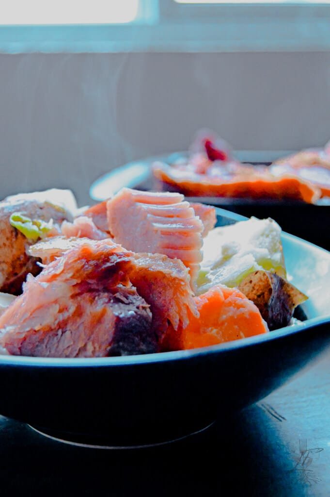 A hearty bowl of Boiled Ham Dinner with ham, cabbage, carrots, and potatoes topped with butter.