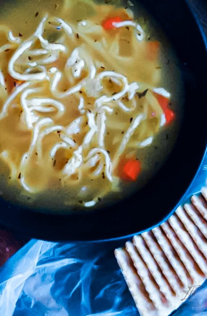 Close-up of chicken noodle soup with chunks of chicken, fresh vegetables, and golden noodles.