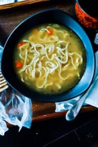 A steaming bowl of homemade chicken noodle soup with tender noodles, rich broth, and fresh herbs.