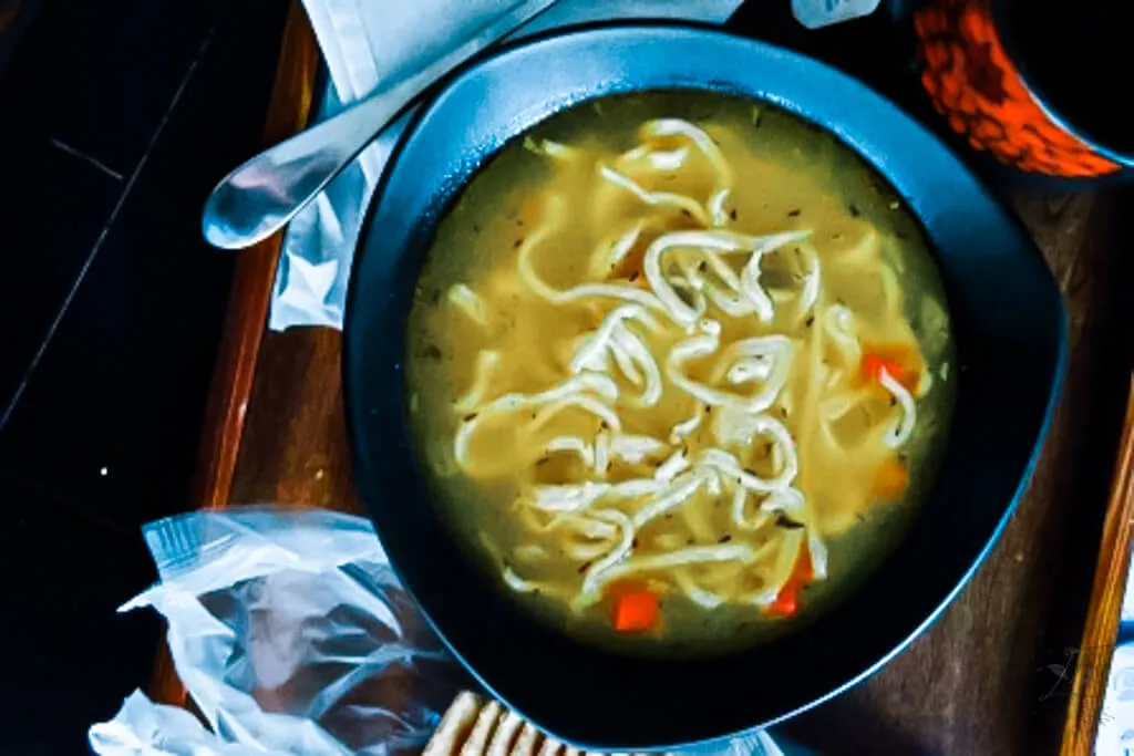 A pot of chicken noodle soup simmering on the stove, filled with chicken, noodles, and colorful vegetables.