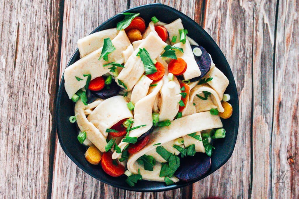 A bowl of freshly cooked homemade egg noodles in savory broth.