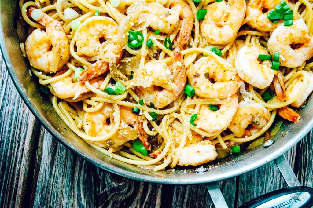 Overhead shot of a plated meal featuring shrimp pasta, sprinkled with grated Parmesan and paired with a fresh green salad.