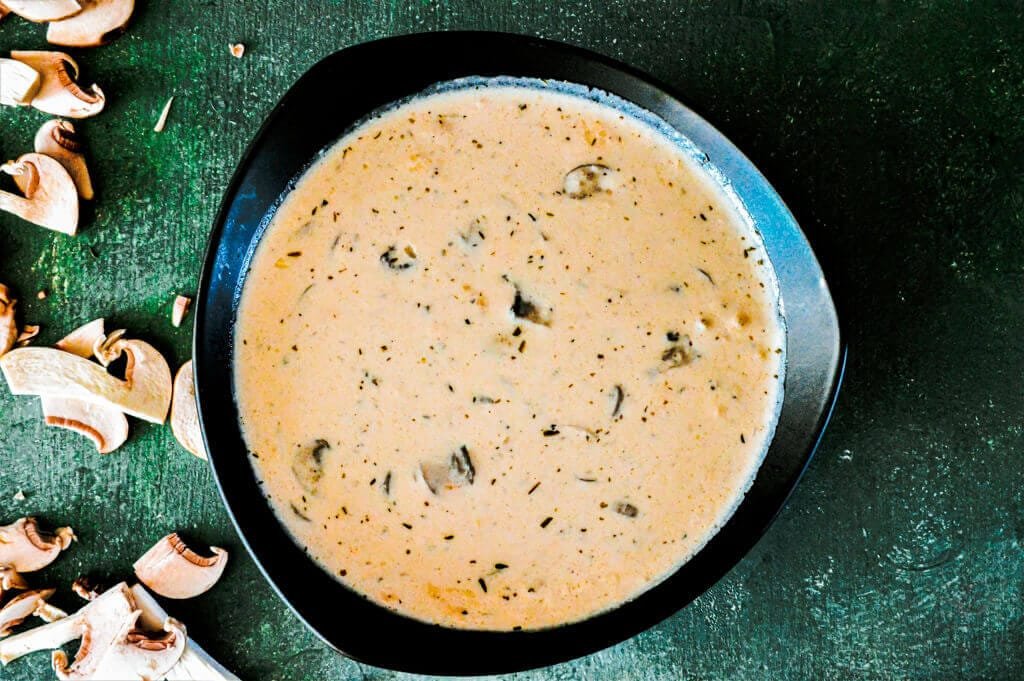 Delicious homemade cream of mushroom soup in a bowl with fresh herbs