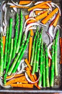 A baking sheet filled with roasted carrots and asparagus, glistening with honey glaze.