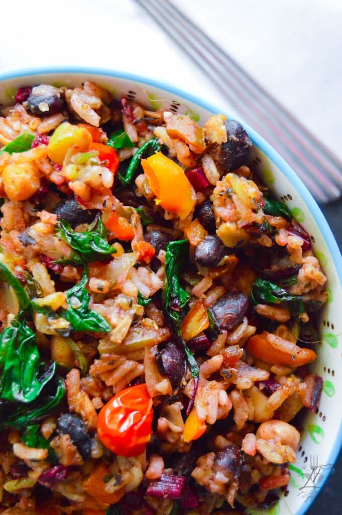 Vegan dirty rice with vegetables, black beans, garbanzo beans, and cilantro lime rice.