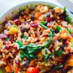 Vibrant bowl of vegan dirty rice with beet greens, peppers, garbanzo beans, tomatoes, and cilantro lime rice.