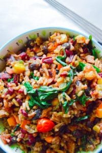 Vibrant bowl of vegan dirty rice with beet greens, peppers, garbanzo beans, tomatoes, and cilantro lime rice.