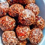 Overhead view of chocolate raspberry oat energy balls stacked in a white bowl.