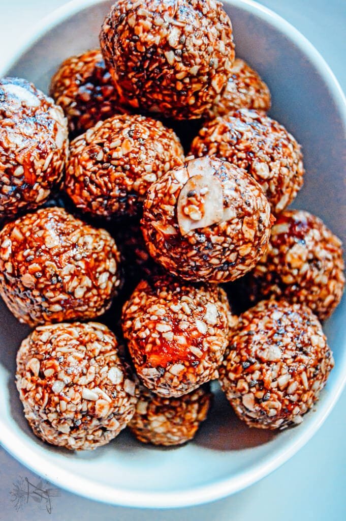 Overhead view of chocolate raspberry oat energy balls stacked in a white bowl.