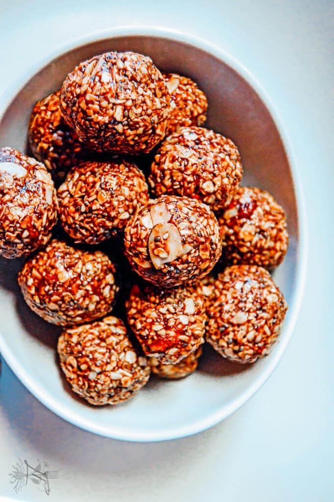 Bowl of glossy chocolate raspberry energy bites made with oats, chia seeds, jam, and hazelnut spread.