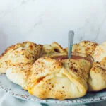 Golden-baked pizza pockets arranged around a bowl of marinara sauce on a rustic ceramic platter.