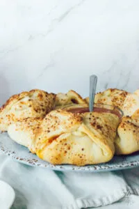 Golden-baked pizza pockets arranged around a bowl of marinara sauce on a rustic ceramic platter.