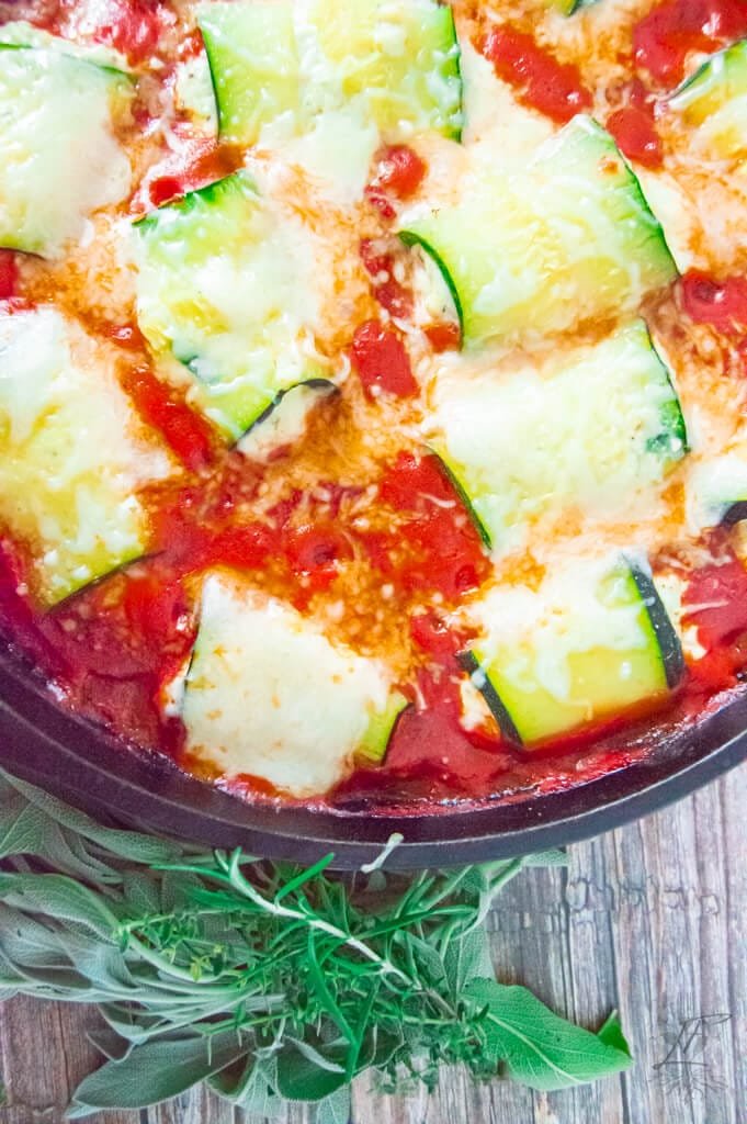 Close-up of baked zucchini rollatini in tomato sauce topped with melted golden cheese.