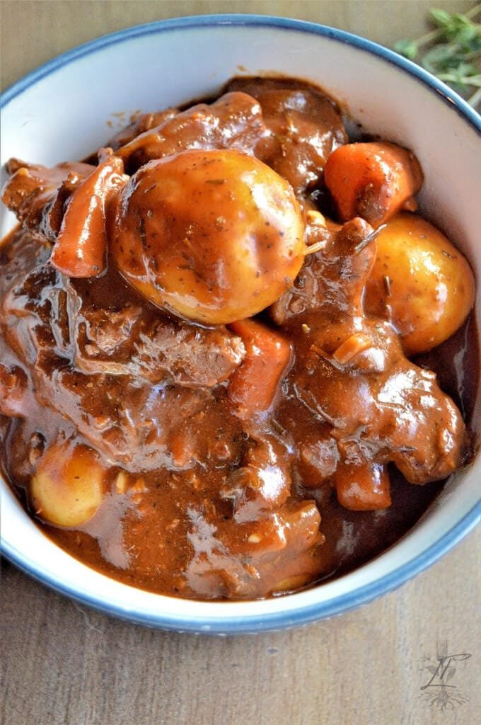 Overhead shot of beef stew with potatoes and carrots nestled in a thick brown gravy, served in a deep bowl.