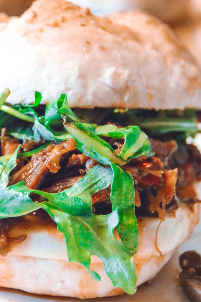 Close-up of a juicy Italian beef sandwich with shredded beef, arugula, and a toasted artisan bun.